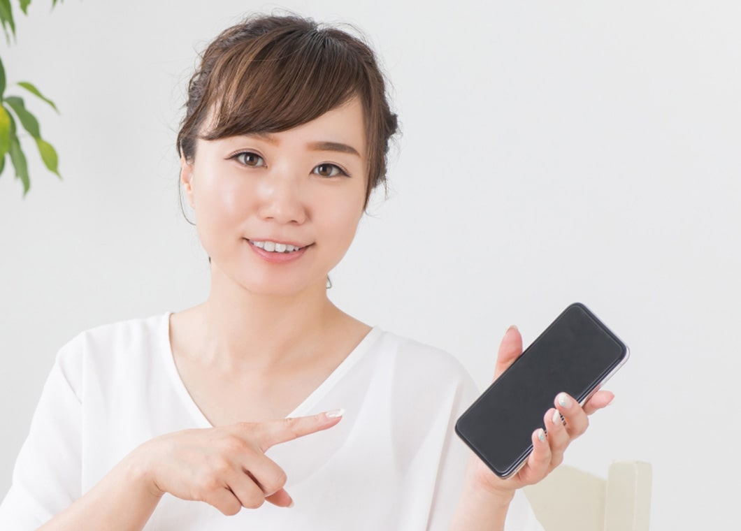 スマートフォンを指さす女性